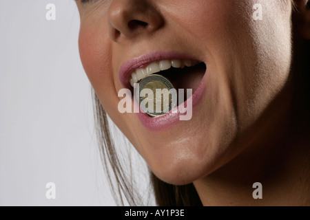 zwei-Euro-Münze zwischen den Zähnen eine junge womans Stockfoto