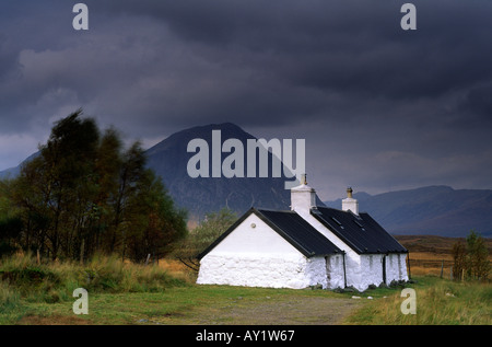 Black Rock Cottage beleuchtet von der Sonne an einem windig und stimmungsvollen Tag in Glen Coe in den schottischen Highlands-UK Stockfoto