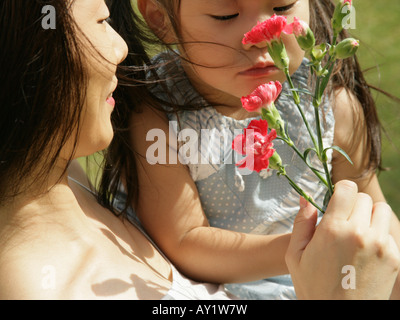 Nahaufnahme eines Mädchens und ihre Mutter, die duftenden Rosen Stockfoto