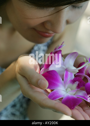 Nahaufnahme einer jungen Frau, die duftende Orchideen Stockfoto