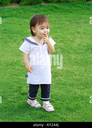 Babymädchen stehen auf einer Wiese Stockfoto