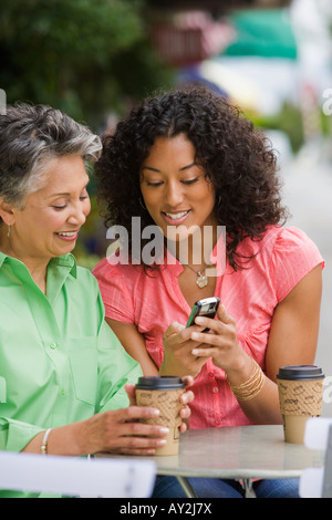 African American Mutter und Erwachsene Tochter Blick auf Handy Stockfoto