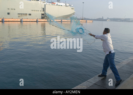 Ein Mann wirft ein Fischernetz aus den Docks im Hafen von Veracruz Mexiko Stockfoto