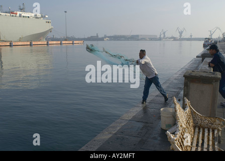 Ein Mann wirft ein Fischernetz aus den Docks im Hafen von Veracruz Mexiko Stockfoto