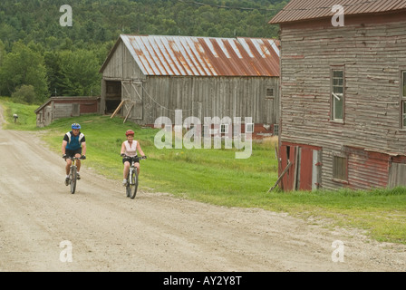 Paar Mountainbikes auf einem ländlichen Feldweg vorbei Reiten verwitterte Scheunen in Warren Vermont an einem bewölkten Sommertag Stockfoto