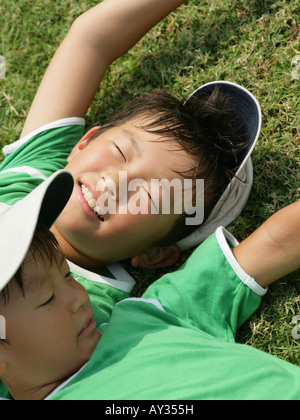 Erhöhte Ansicht von zwei Jungs auf dem Rasen liegend Stockfoto