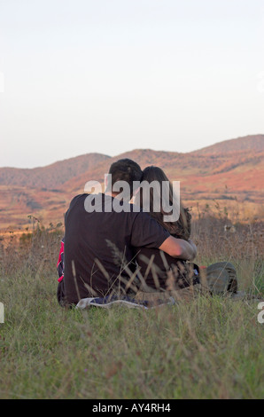Junges Paar sitzt im Feld umarmt den Kopf Rückansicht Stockfoto