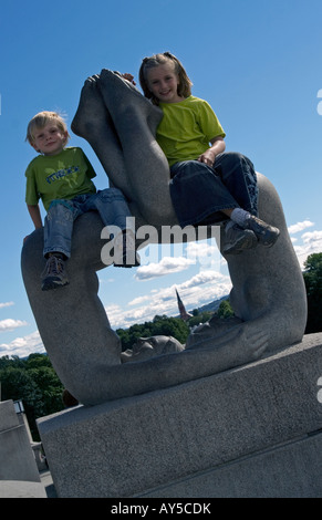 Jungen und Mädchen sitzen auf einer der Statuen im Vigeland Sculpture Garden in Frognerpark, Oslo, Norwegen Stockfoto