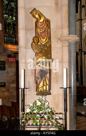 London Southwark Cathedral, moderne vergoldete Statue der Jungfrau Maria hielt Jesus mit Blütenpracht & Kerzen Stockfoto