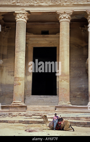Beduinen sitzen auf einem Kamel vor Al Khazneh, einem alten Felsen gehauene Gebäude in Petra, Jordanien. Stockfoto
