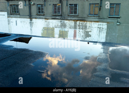 Reflexionen der goldene gelbe Wolken in eine Wasserpfütze auf einem Dach in der Innenstadt Dublin Irland Stockfoto