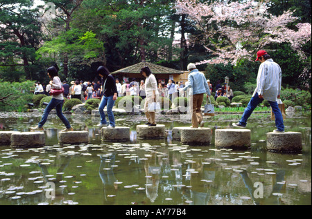 Japanische Jugendliche zu Fuß über Trittsteine in Teich Heian Glanz in Kyoto Japan Stockfoto