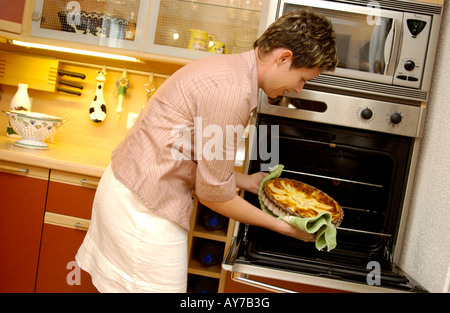 Frau, Kochen - putting eine Quiche / Torte im Ofen in ihrer Küche zu Hause Stockfoto