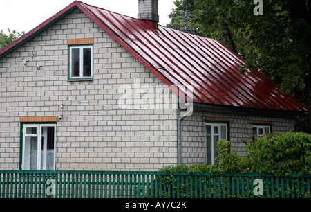 Zweistöckiges Haus mit leuchtend roten Metall-Dach. Grün trimmen auf Unterseite des Hauses. Baum im Hintergrund Stockfoto