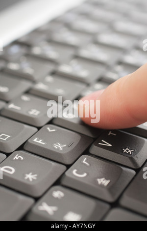 Nahaufnahme eines Benutzers Finger drücken Laptop-Tastatur mit englischen und chinesischen Zeichen Stockfoto