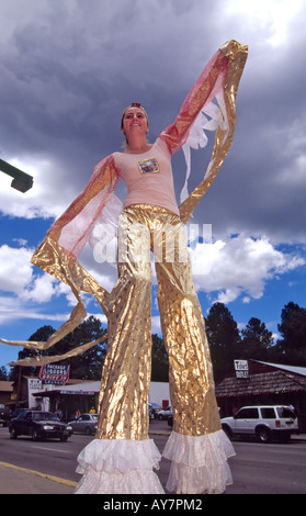 Ein großes Teenies Mädchen winkt der Menschenmenge während Balancieren auf Stelzen, in der Spieler-Straßenfest in Ruidoso, New Mexico. Stockfoto