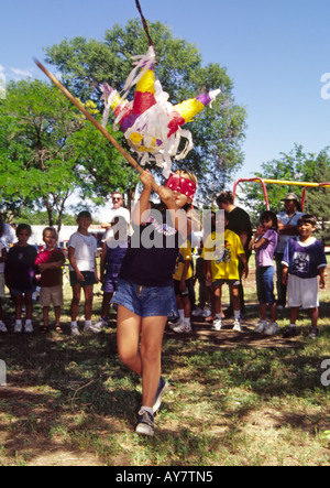 Ein mit verbundenen Augen hispanischen Mädchen nimmt einen Schlag am Preis-gefüllte Pinata, die Pinata fest in Poe Mais Park, Roswell, New Mexico. Stockfoto