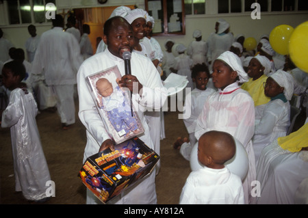 Schwarzer britischer Kirchenpastor mit Spielzeug für schwarze britische Kinder, weiße Puppe Celestial Church of Christ London UK. HOMER SYKES der 1990er Jahre Stockfoto