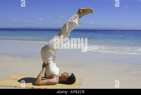 Junge Frau an einem Strand in der Yoga-Haltung eine halbe Schulter stehen Stockfoto