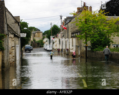 Kinder stehen in der überfluteten Straße der Milton Street in Fairford Stockfoto