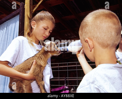 Herr 724 Ashley Lakey und Freund erfahren Sie mehr über die Pflege und Fütterung der ein Zicklein in der Faser Fest in Lincoln, New Mexico. Stockfoto