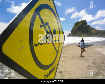 Surfer, die hinunter Piha Strand mit der Gefahr schwimmen abmelden Stockfoto