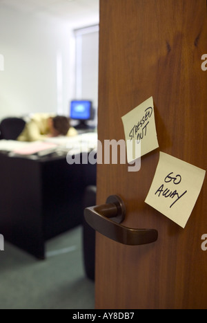 Betonte, Go Away post seine draußen vor der Tür, wie Mitarbeiter auf Schreibtisch Kopfstützen Stockfoto