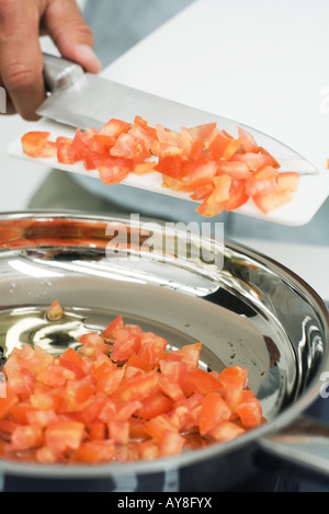 Mann, kratzen, gewürfelte Tomaten in Topf mit Messer beschnitten Ansicht Stockfoto