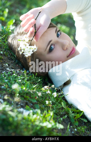 Teenager-Mädchen auf dem Boden liegend mit Blumen, lächelnd in die Kamera Stockfoto