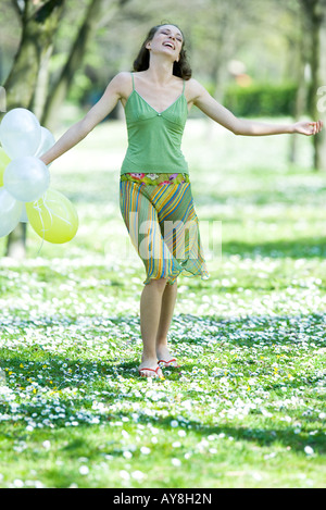 Junge Frau Wandern in Wiese, mit Luftballons, Arme, Lächeln Stockfoto