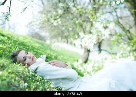 Teenager-Mädchen liegen in Rasen, halten Blumen, Augen geschlossen Stockfoto