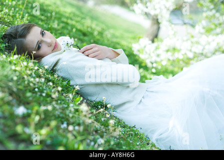 Teenager-Mädchen auf dem Boden liegend mit Blumen, Blick in die Kamera Stockfoto