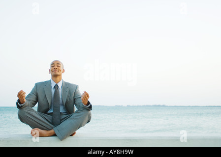 Geschäftsmann, sitzen im Lotussitz am Strand, Augen geschlossen Stockfoto