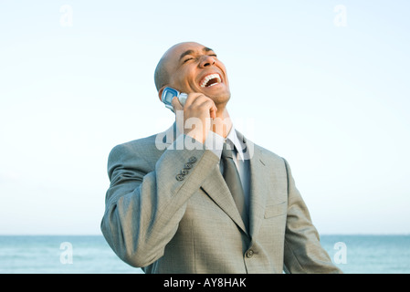 Geschäftsmann am Strand mit Handy, lachen, Augen geschlossen Stockfoto