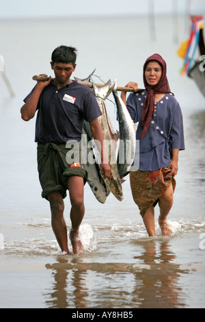 Mann und Frau tragen spanische Makrele am Pol Fischerdorf Ban Batu Ko Libong Insel Thailand Stockfoto