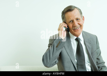 Geschäftsmann mit Handy, lächelt in die Kamera Stockfoto