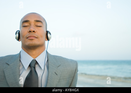 Geschäftsmann hören Kopfhörer am Strand, Augen geschlossen, Nahaufnahme Stockfoto