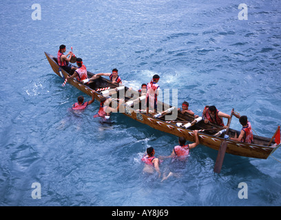 Männer der Brücke springt und klettert in ihr Boot beim Drachenbootrennen am Oojima Ari (Haarri Hari Baari) Tamagusku Dorf Okinawa Stockfoto