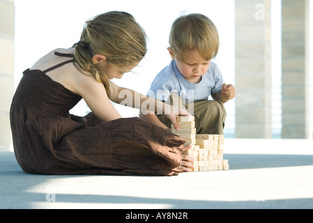 Bruder und Schwester sitzen auf dem Boden gestapelt Bausteine Stockfoto