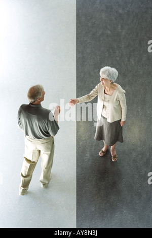 Paar steht im geteilten schwarzen und weißen Stock, Frau haltende Hand, Gruß, hoher Winkel anzeigen Stockfoto