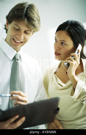 Männlichen und weiblichen Kollegen stehen nebeneinander, Frau mit Handy, Mann auf der Suche bei binder Stockfoto