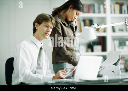 Männlichen und weiblichen Kollegen am Schreibtisch, Mann mit Laptop-Computer, Frau mit Telefon Stockfoto