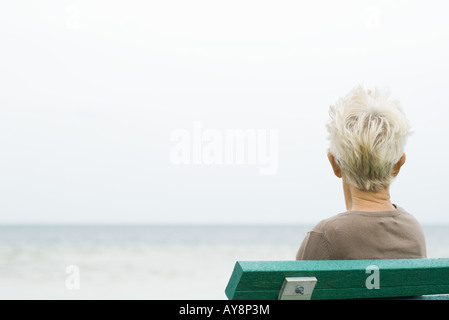 Ältere Frau sitzt in der Nähe von Meer, Rückansicht Stockfoto