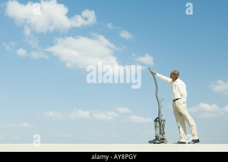 Mann stehend, Türen, Staubsaugen Wolken, Seitenansicht Stockfoto