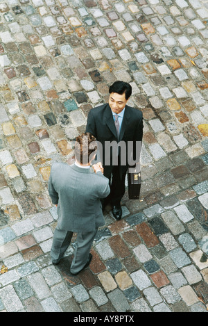 Zwei Geschäftsleute von Angesicht zu Angesicht stehen, Hände schütteln, erhöhte Ansicht Stockfoto