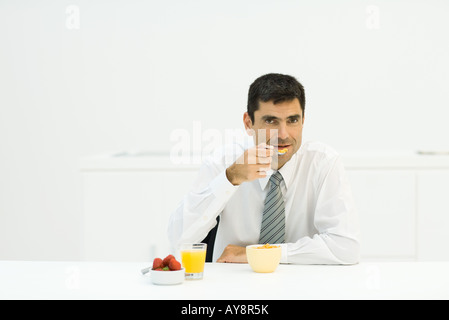 Mann am Tisch sitzen, gesundes Frühstück, Blick in die Kamera