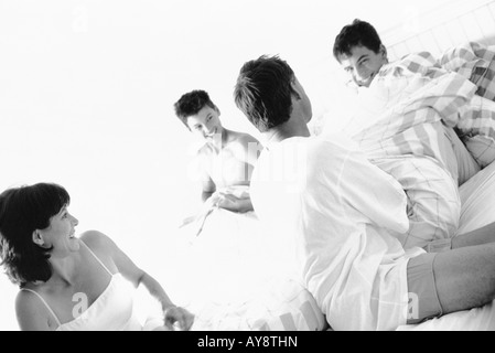 Familie gekleidet im Pyjama, auf Bett, sitzt lächelnd in Lachen Stockfoto