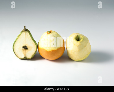 Birne, Orange und Apfel in einer Reihe, alle teilweise geschält Stockfoto