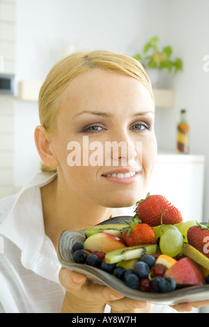 Frau hält verschiedene Früchte auf Platte, in die Kamera Lächeln Stockfoto