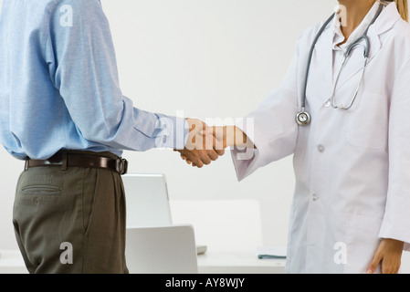 Ärztin, schüttelt die Hand des Mannes, Seitenansicht, beschnitten Stockfoto